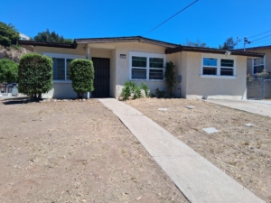 Single-story house with beige walls, a low-maintenance front yard, and a concrete walkway leading to the front door.
