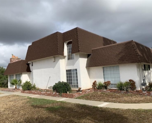 42740d40-4eb3-40ed-838d-73f0b3206bfc Two-story white house with a brown mansard roof, large windows, and a spacious layout beneath a cloudy sky.